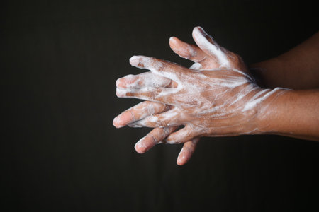 young man washing hands with soap on black backgroundの写真素材