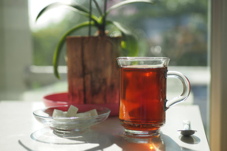 early morning green tea and sugar on table near windowの写真素材