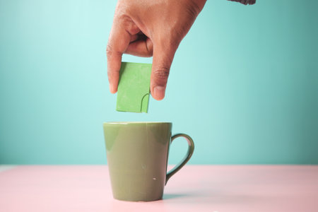 young man putting artificial sweetener in tea,の写真素材