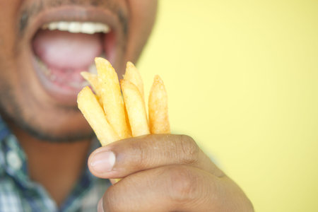 young man eating french fries close upの写真素材