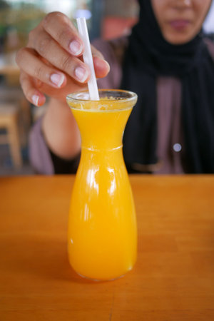 women hand holding a glass of orange juiceの写真素材