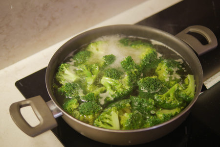cooking broccoli in pan on electric stoveの写真素材