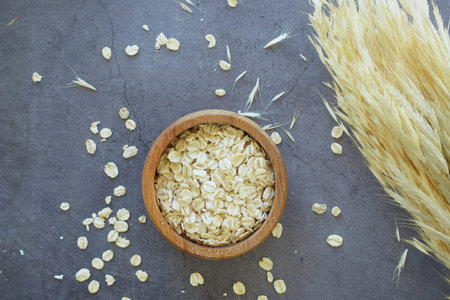oats flakes in a a wooden bowl on black background