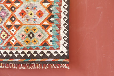 f Seamless colorful carpet hanging on a red wall
