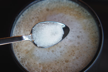 dropping sugar from a spoon in a coffee cup ,の写真素材