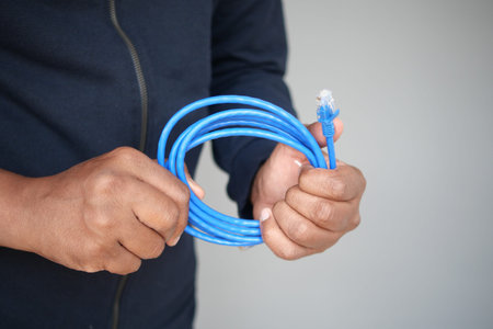 A closeup of hands holding a coiled blue Ethernet cable for a network connection