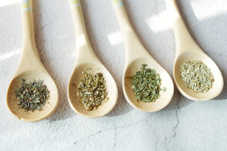 Four wooden spoons holding various spices on a tableの写真素材