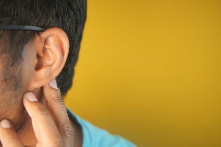 young man having ear pain touching his painful ear ,