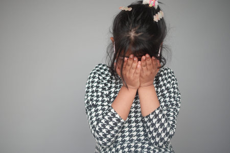 a upset child girl cover her face with hand