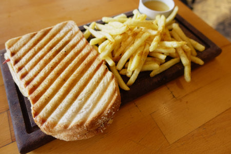 Grilled Panini Sandwich and Crispy French Fries beautifully served on a Wooden Board