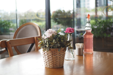 A table in a cozy cafe setting, embellished with a flower arrangement and a bottled beverageの写真素材