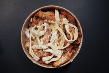 A comforting Chicken Alfredo Pasta dish is presented in a bowl on a dark surfaceの写真素材