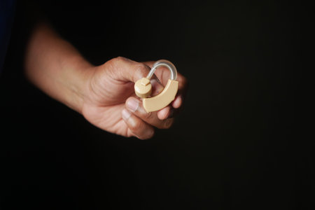 holding a Hearing aid equipment on black background