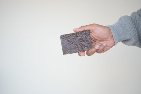 hand holding a dark chocolate candy with copy space
