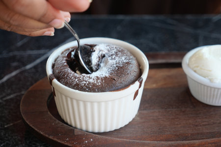 Delicious Chocolate Lava Cake with Powdered Sugar and Whipped Cream on Wooden Plateの写真素材