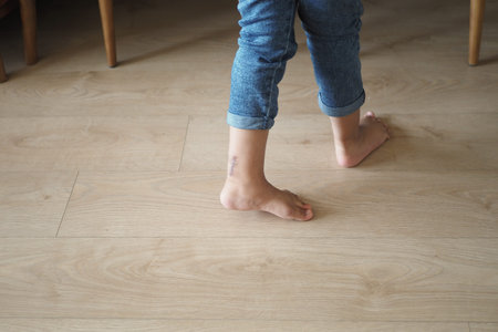 A carefree child walks barefoot on a wooden floor, cherishing innocence and exploration