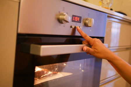woman hand setting temperature control on oven.の写真素材