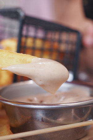 Closeup of a French fry being dipped in sauce, a tempting appetizer with a crispy appealの写真素材