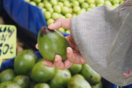 young woman hand holding avocado shopping at retail store