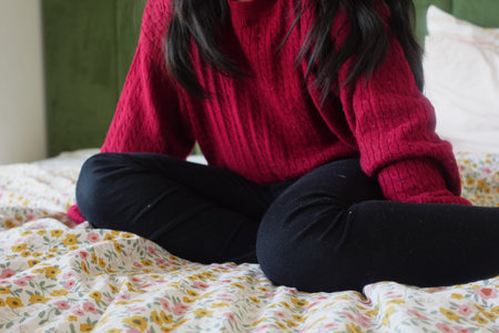 Indulge in a Comfortable Moment wearing a Red Sweater while lounging on a Floral Bedspread