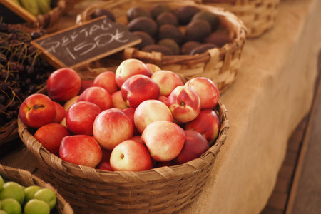 A beautiful display of fresh, ripe nectarines in a rustic woven basket at a local farmers marketの写真素材