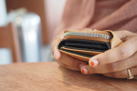 An Elegant Hand Gently Holding a Stylish Wallet That Features a Convenient Zipper Closure