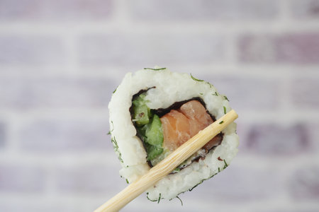 Delicious Fresh Sushi Roll with Salmon and Colorful Vegetables Served on Elegant Chopsticksの写真素材