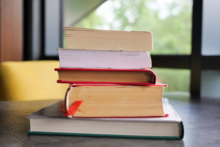 An open book with its pages gently turning rests on a wooden table in the breezeの写真素材