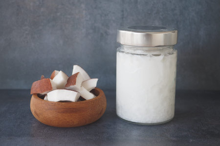 slice of fresh coconut and bottle of oil on a tableの写真素材