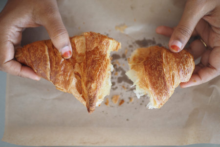 closeup of hand breaking a croissant bun