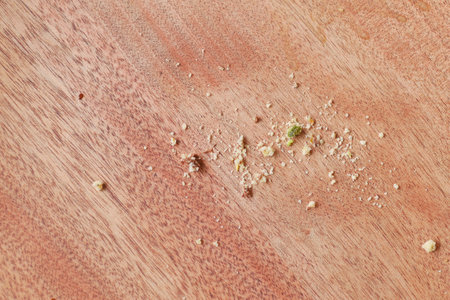 CloseUp View of Tiny Crumbs Scattered Across a Wooden Kitchen Surfaceの写真素材