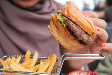 woman hand holding a beef burger enjoying her mealの写真素材