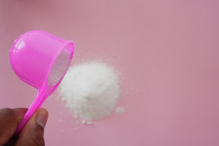Washing powder pouring from a plastic spoonの写真素材