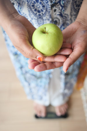 A person is holding a fresh green apple standing on weight machineの写真素材