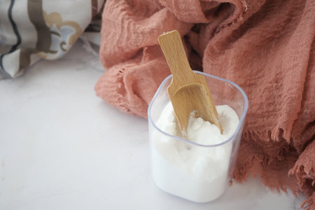 Baking soda in a container and cloths on tableの写真素材