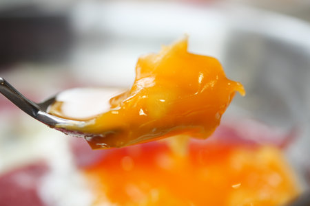 CloseUp of a Spoon with a Runny Egg Yolk on Fried Egg Whites, a tasty and healthy breakfastの写真素材