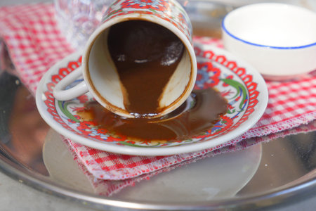 A Traditional Cup of Spilled Turkish Coffee Placed on a Beautifully Decorative Plateの写真素材