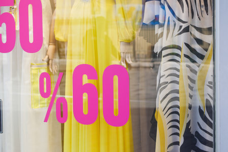 A vibrant and colorful fashion display featuring an eyecatching discount sign in the storefrontの写真素材