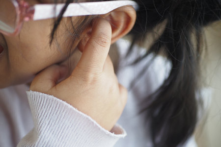child having ear pain touching his painful ear ,の写真素材