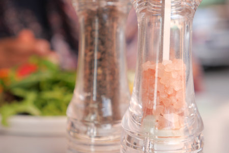 Delightful Salt and Pepper Shakers Accompanied by a Delicious Meal Presented on Tableの写真素材