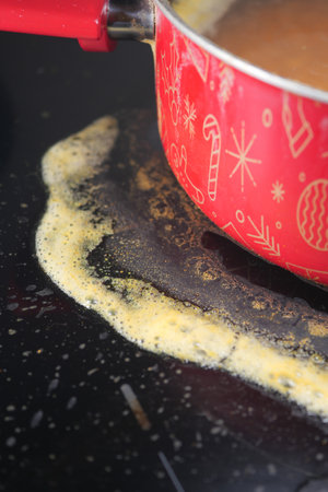 A Bubbling Pot of Soup Sitting on a Stovetop with Spillage Over the Edges Creating a Big Messの写真素材