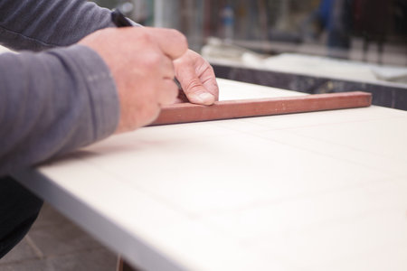 A skilled craftsman meticulously working with colorful tiles on a sturdy workbenchの写真素材