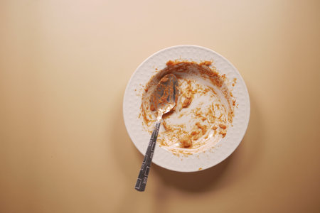 An empty plate with a spoon rests after a meal has been enjoyedの写真素材