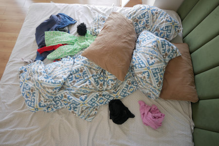 A Messy Bed with Various Colorful Clothes and Soft Pillows Is a Cozy and Casual Space