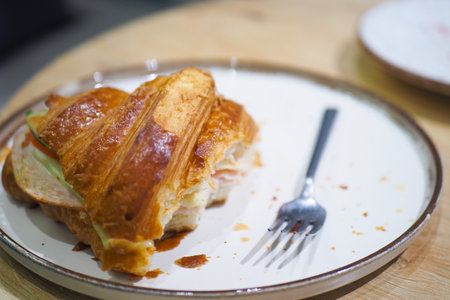 A Freshly Baked Croissant is beautifully presented with a Fork on a Plate, inviting to eatの写真素材