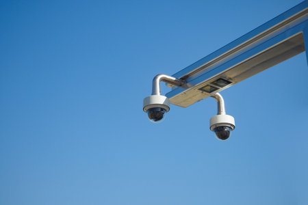 Surveillance Cameras Positioned Against a Clear Blue Sky on a Bright Day of Activitiesの写真素材