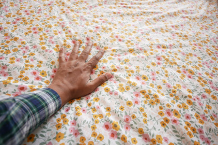 A hand resting gently on a beautifully floral patterned fabric with vibrant and colorful designsの写真素材