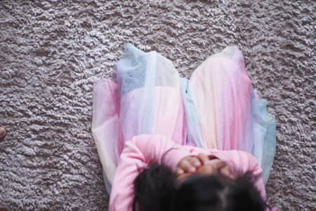 A Young Child is Sitting Comfortably on a Soft, Cozy Rug While Wearing a Colorful Tutu Dressの写真素材