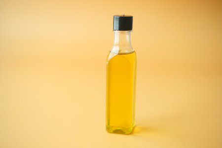 A Clear Glass Bottle filled with Cooking Oil set against a Bright Yellow Backgroundの写真素材