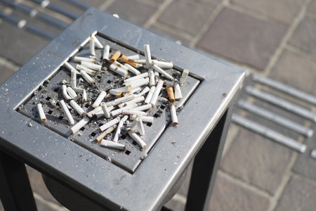 The collection of cigarette butts found in the outdoor ashtray on a public streetの写真素材